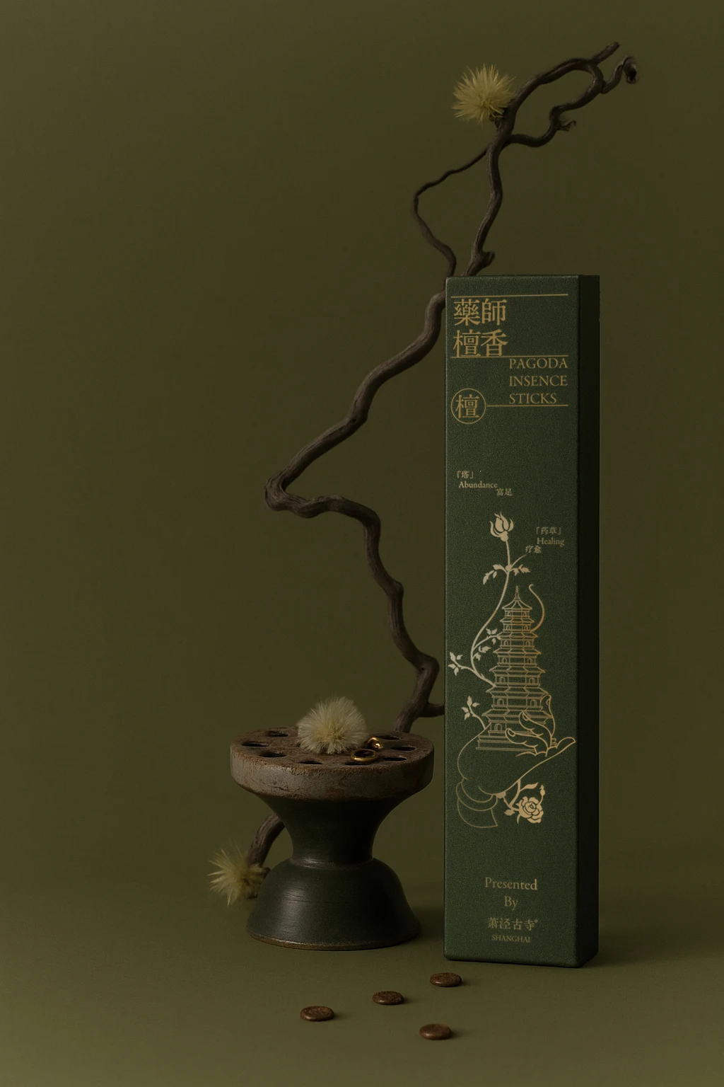 A tall dark green incense package beside an incense burner and stones.